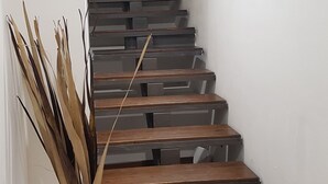 Eine Treppe mit Holzboden und einer weißen Vase mit getrockneten Pflanzen auf der linken Seite.