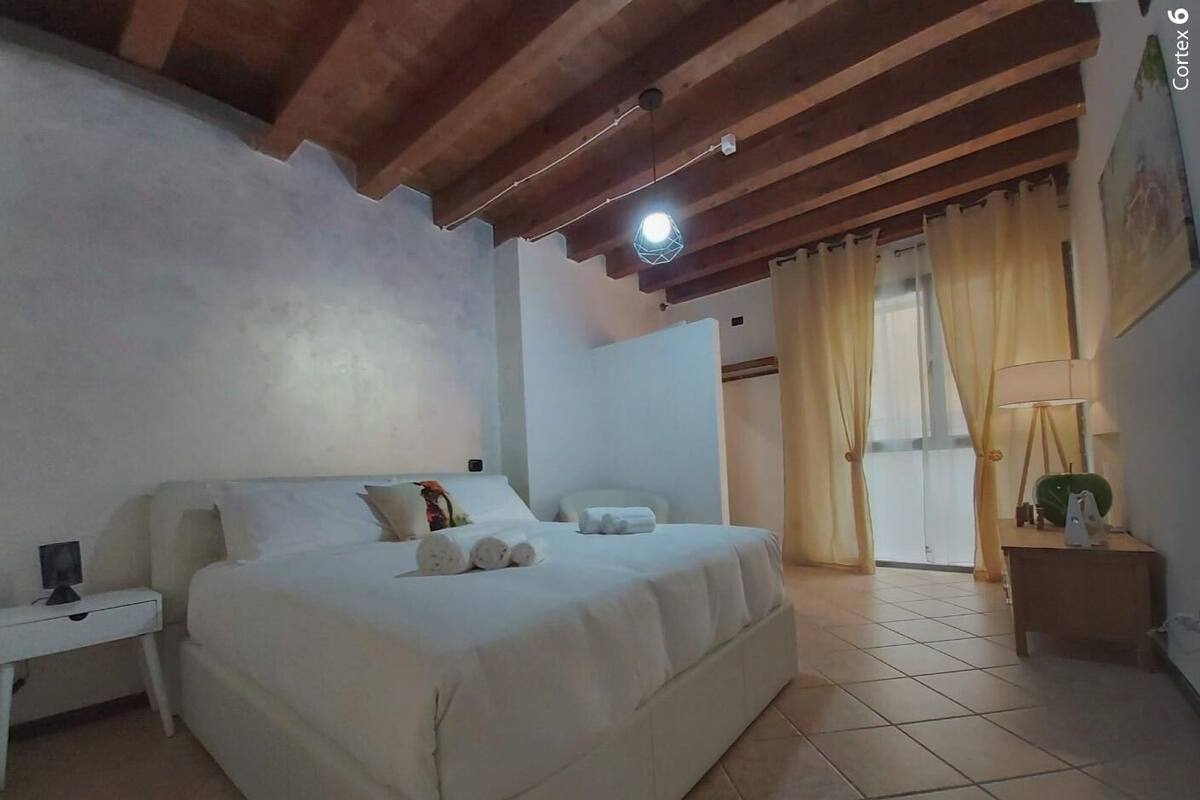 A bedroom with a bed, a nightstand, a lamp, and a window with curtains.