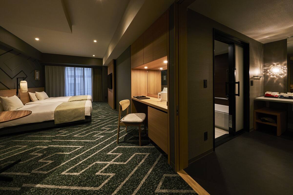 Una habitación de hotel con cama, escritorio, silla y baño.