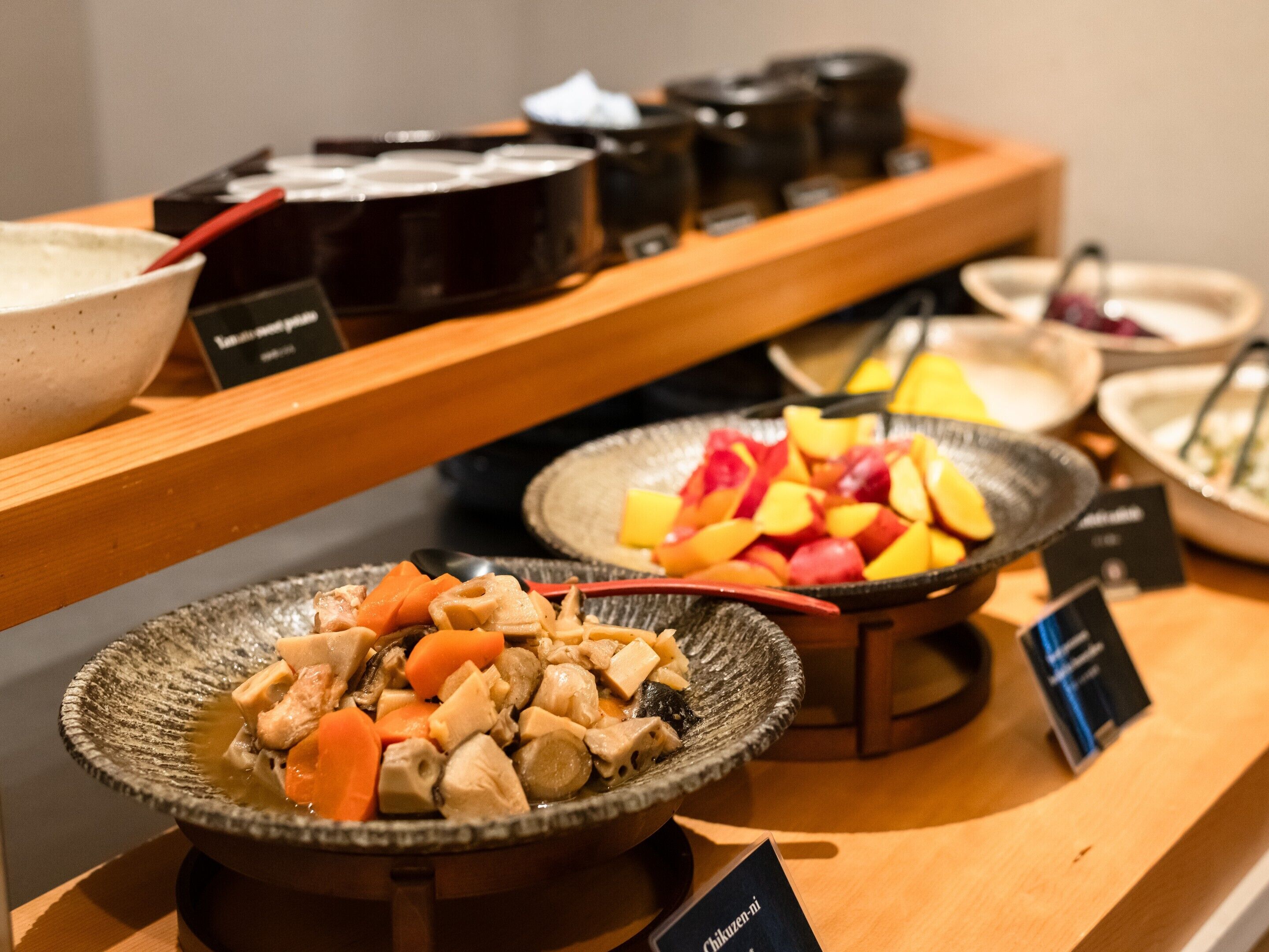 A buffet with various dishes including a bowl of chicken and vegetables, a bowl of fruit, and several condiment containers.
