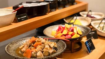 A buffet with various dishes including a bowl of chicken and vegetables, a bowl of fruit, and several condiment containers.