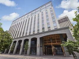 Un hotel moderno con una entrada amplia, varios pisos y un cartel llamativo.