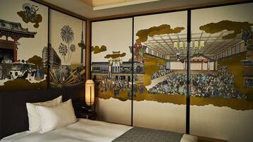 Ein traditioneller japanischer Raum mit Tatami-Boden, einem Bett mit weißer Bettwäsche und einer Schiebetür mit einem Wandgemälde, das historische Szenen zeigt.