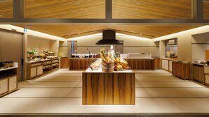A modern kitchen with wooden accents, a central island with fruits and vegetables, and a chef in uniform. - Asakusa View Hotel Annex Rokku (Tokyo)
