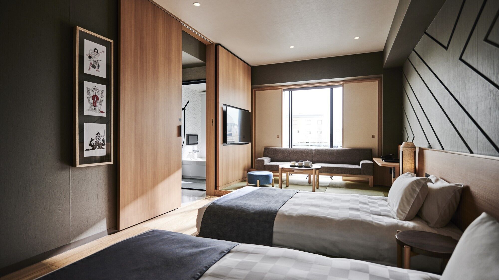 Een moderne hotelkamer met twee bedden, een bank, een televisie en een groot raam.