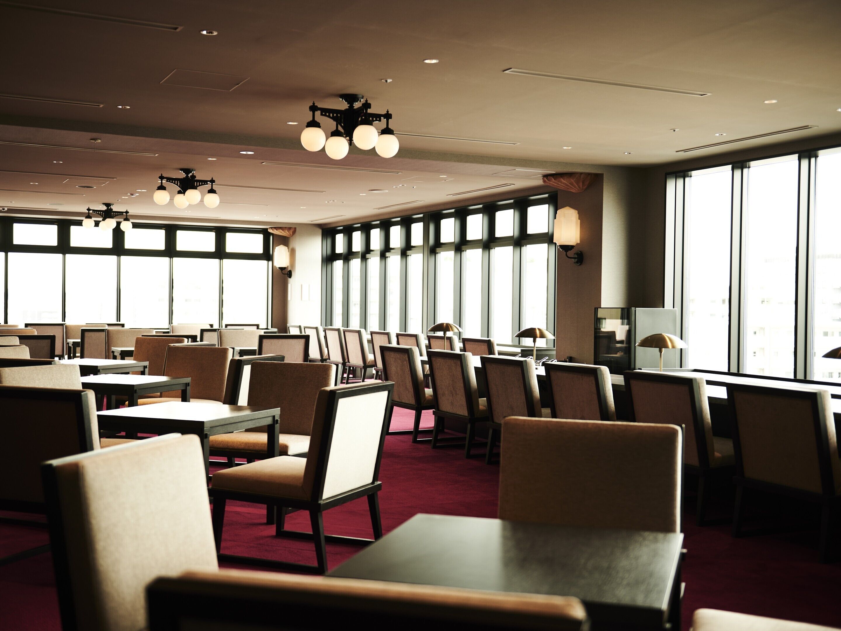 Un vaste espace dédié à la salle à manger, doté de hauts plafonds, de nombreuses tables et chaises, et de grandes fenêtres laissant entrer la lumière naturelle.