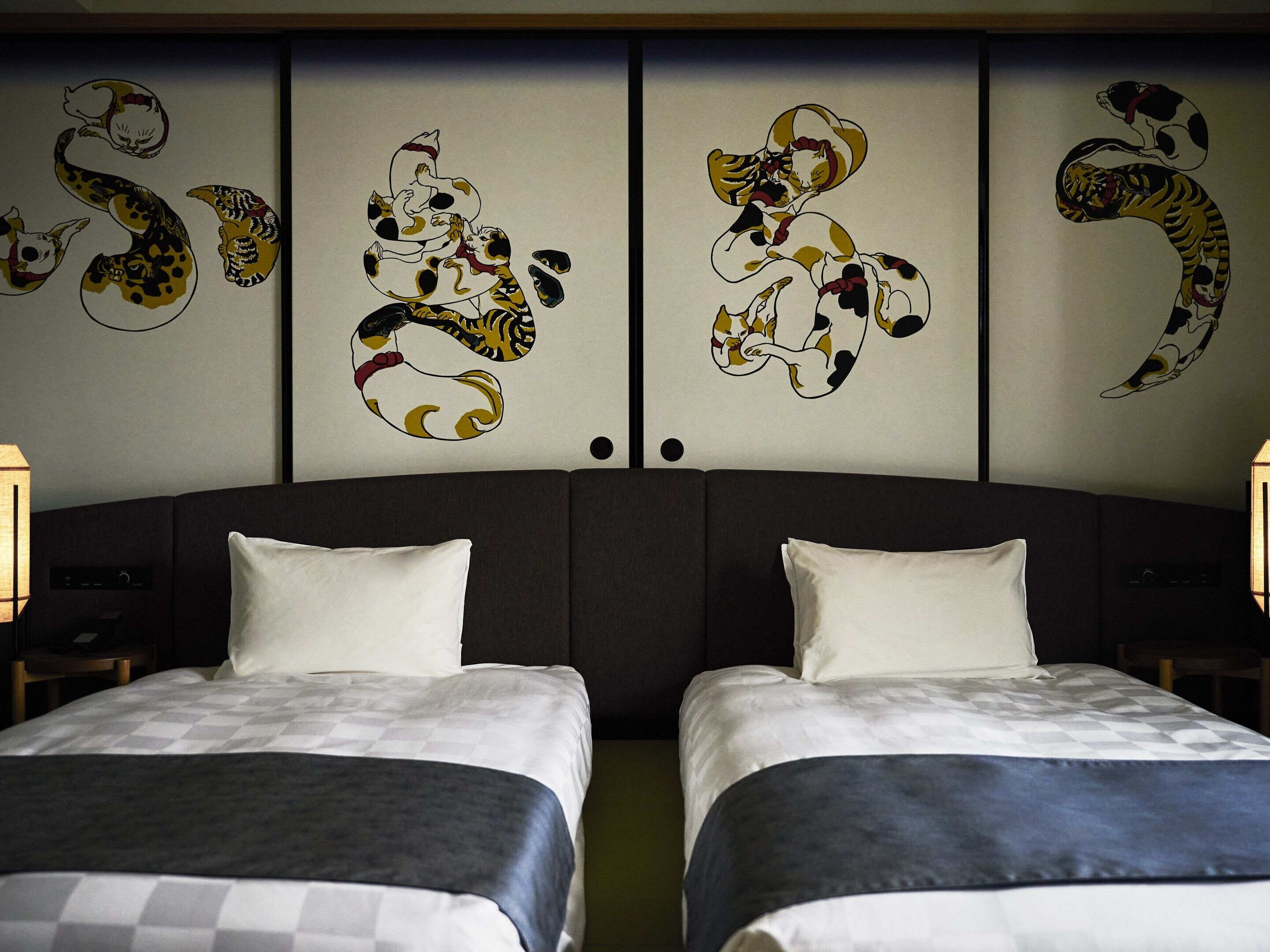 Ein Hotelzimmer mit zwei Betten, einem dunklen Kopfteil und einer Wand mit abstrakter Tierkunst.