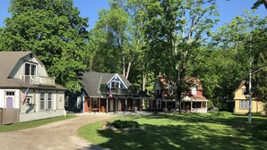 A traditional two-story house with a porch, a small front yard, and a flag.