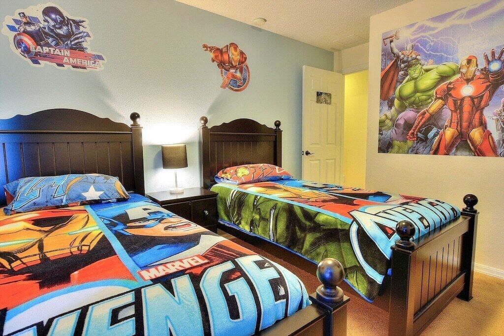 Une chambre à coucher avec deux lits, chacun recouvert d’une couvre-lit aux motifs de Marvel.