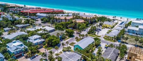 Vista aérea de una zona residencial costera con casas, una playa y un cielo azul despejado.