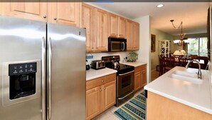A modern kitchen with stainless steel appliances, wooden cabinets, and a built-in water dispenser. - Spacious 3 Bedroom, 2 1/2 bath Condo, Steps to the beach! 2 pools and Hot Tub! (Bradenton Beach)