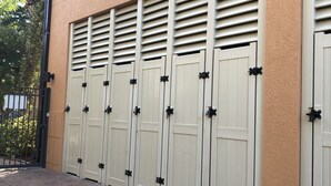 A row of beige double doors with black handles, set against a peach-colored building facade. - Spacious 3 Bedroom, 2 1/2 bath Condo, Steps to the beach! 2 pools and Hot Tub! (Bradenton Beach)