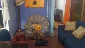 A living room with a sofa, a glass coffee table, a lamp, and a laptop. - Bio Bamboo Bed and Breakfast (Ambato)