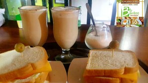 Two sandwiches on plates, a glass of milk, and a milkshake on a table. - Bio Bamboo Bed and Breakfast (Ambato)