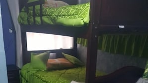 A bunk bed with green bedding, a window with curtains, and a small table with a white object on it. - Bio Bamboo Bed and Breakfast (Ambato)