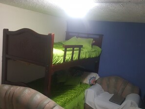 A bunk bed with a green mattress and pillows, a wooden headboard, and a white blanket on the lower bunk. - Bio Bamboo Bed and Breakfast (Ambato)
