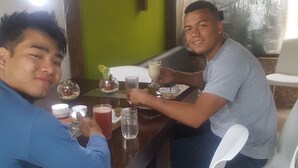 Two people sitting at a table with drinks and a bowl of snacks. - Bio Bamboo Bed and Breakfast (Ambato)