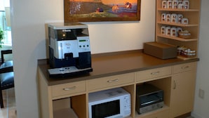 Une petite cuisine équipée d’une machine à café, d’un four à micro-ondes, d’un grille-pain et d’étagères avec des bocaux.
