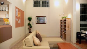 Un salon avec un canapé beige, une table basse, une plante, un tableau encadré et une bibliothèque.