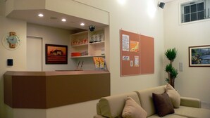 Un espace d’accueil comprenant un comptoir, une horloge, un tableau d’affichage, un tableau encadré et un canapé.