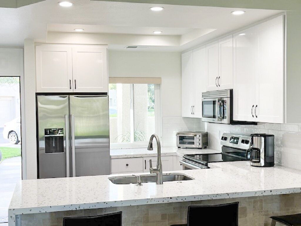 A modern kitchen with white cabinets, stainless steel appliances, and a large island with a sink.