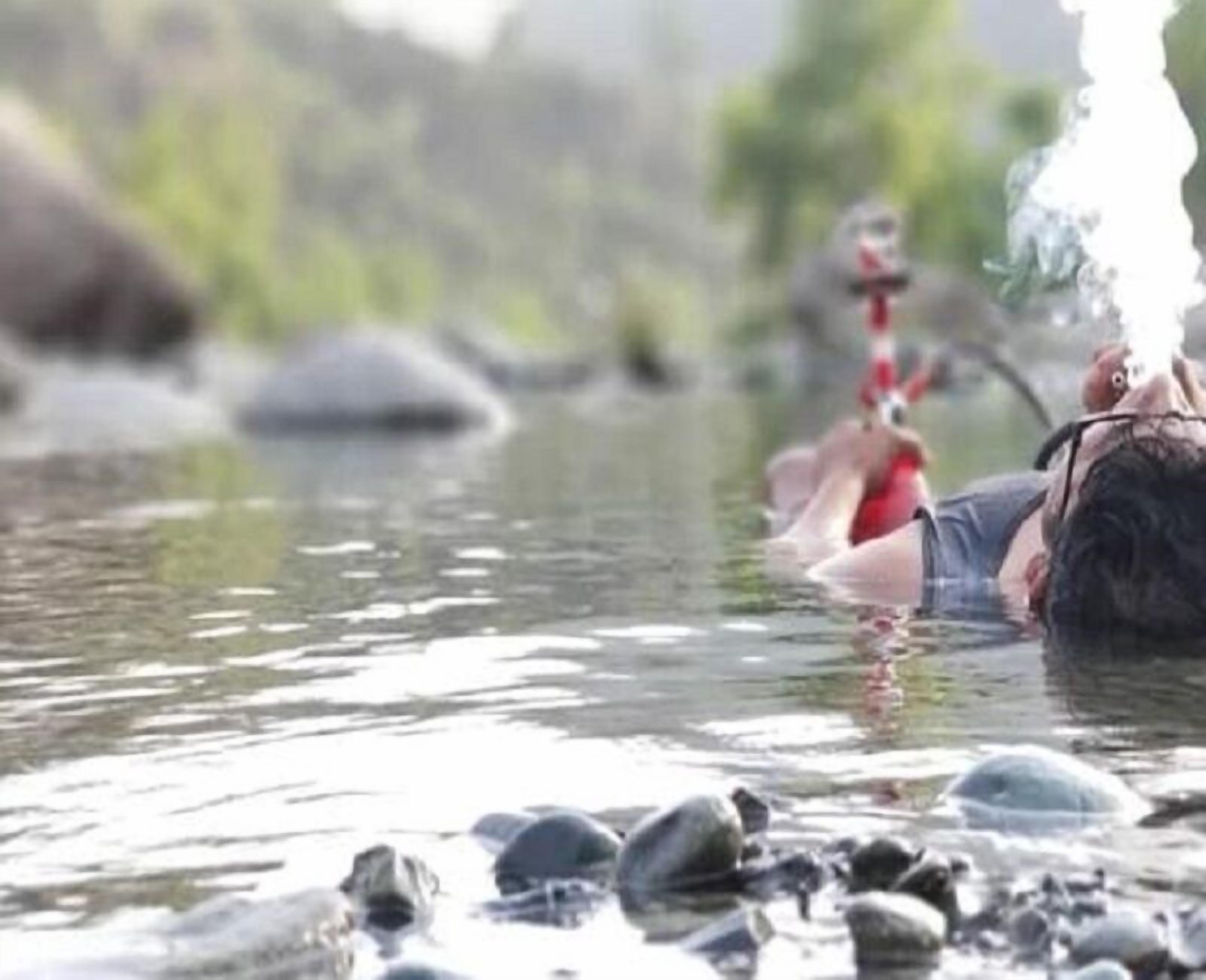 Una persona en un río con rocas y un fondo desenfocado.