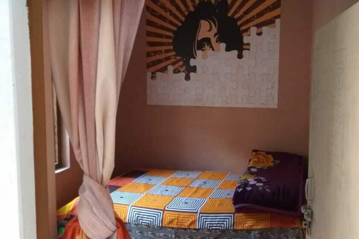 Ein kleiner, gemütlicher Raum mit einem Bett, einer Wanddekoration und einem Vorhang.