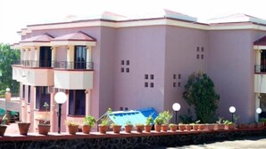 A large, multi-story building with balconies and a covered entrance area. - The Dhanhills - A Valley View Hotel In Panchgani (Mahabaleshwar)