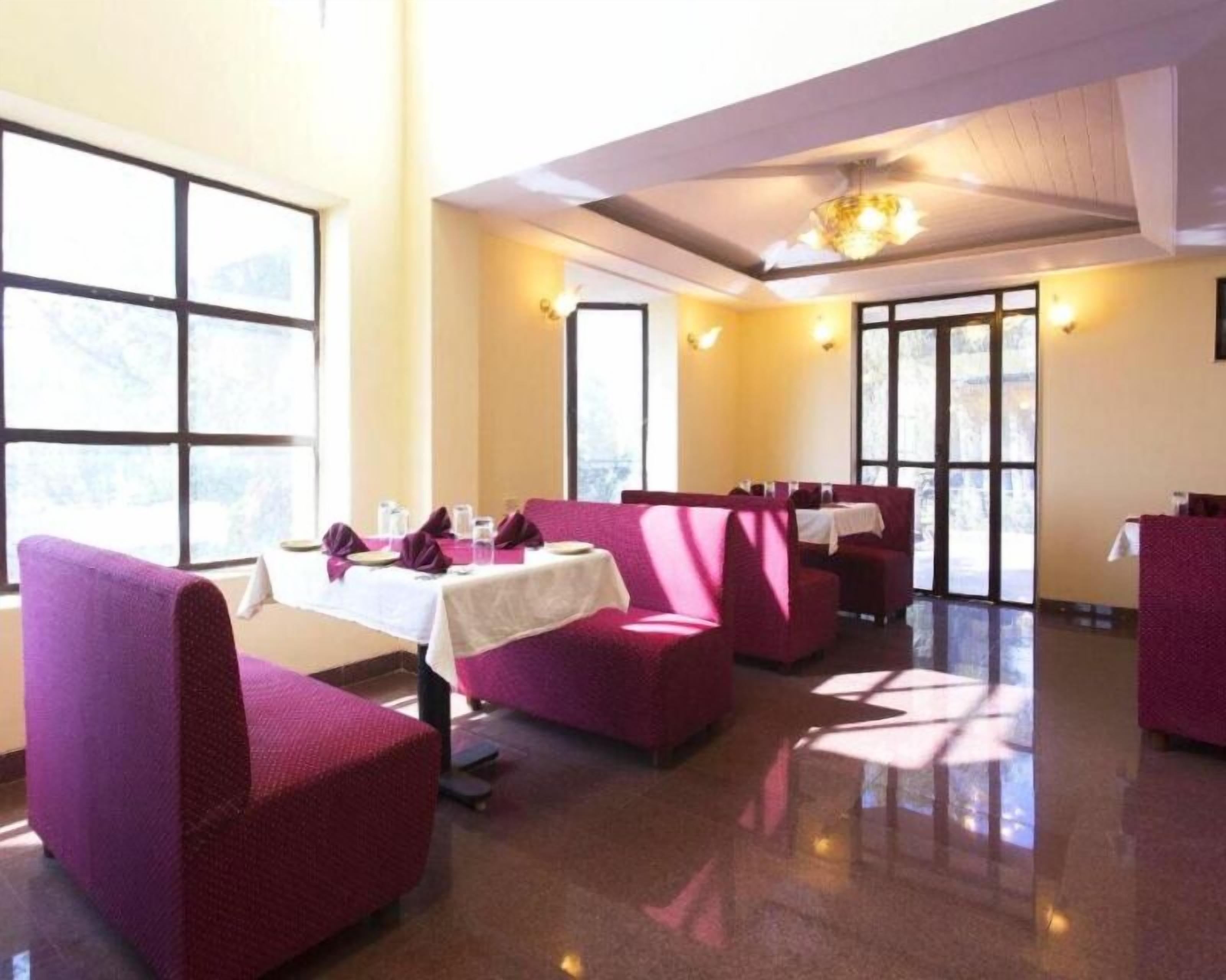 A restaurant with high ceilings, large windows, and purple seating.