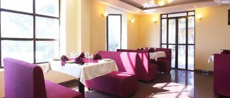 A restaurant with high ceilings, large windows, and purple seating.