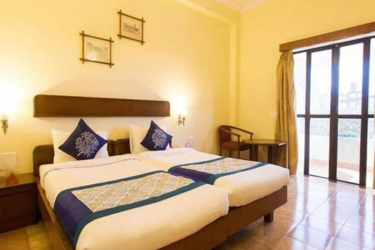 A double bed with a wooden headboard, two bedside tables, and a nightstand. There is a chair and a small table next to the bed.