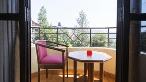 A balcony with a wooden floor, a red chair, and a small table with a red object on it. - The Dhanhills - A Valley View Hotel In Panchgani (Mahabaleshwar)