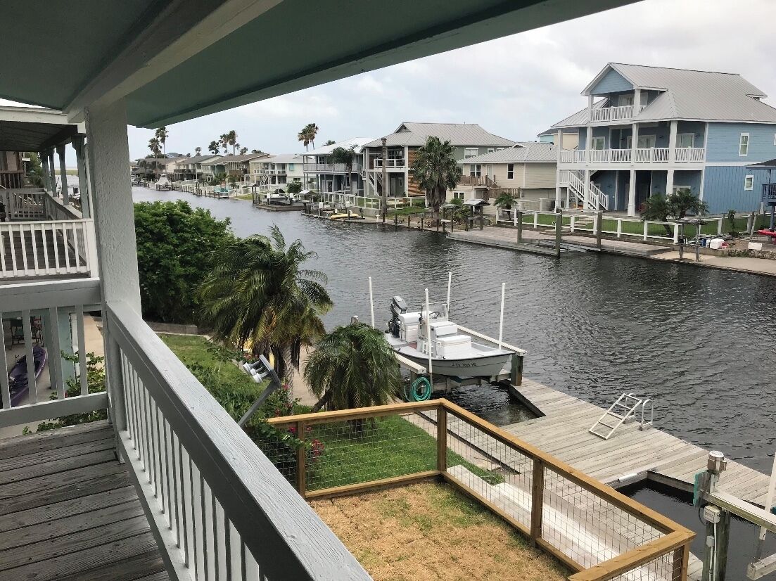 A waterfront property with a dock, a boat, and a view of other buildings across the water.