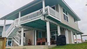 A two-story house with a covered porch, a staircase, and a patio area. - Reel’em Inn - a Waterfront Home on the Canal (Aransas Pass)