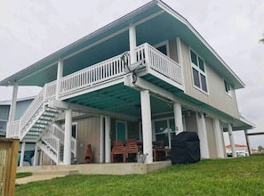 A two-story house with a covered porch, a staircase, and a patio area. - Reel’em Inn - a Waterfront Home on the Canal (Aransas Pass)