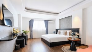 Une chambre d’hôtel moderne équipée d’un grand lit, d’un bureau, d’une chaise, d’une table ronde et d’un miroir.