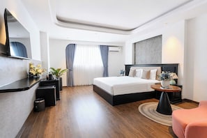 A modern hotel room with a large bed, a desk, a chair, a round table, and a mirror.