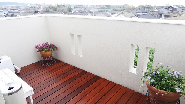 A rooftop terrace with a wooden deck, two potted plants, and a white wall with small windows. - Family Lodge Hatagoya Kagoshimatarumizu (Tarumizu)