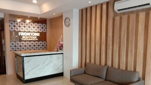 Un espace d’accueil avec un comptoir en marbre, un canapé et un mur revêtu de panneaux en bois.