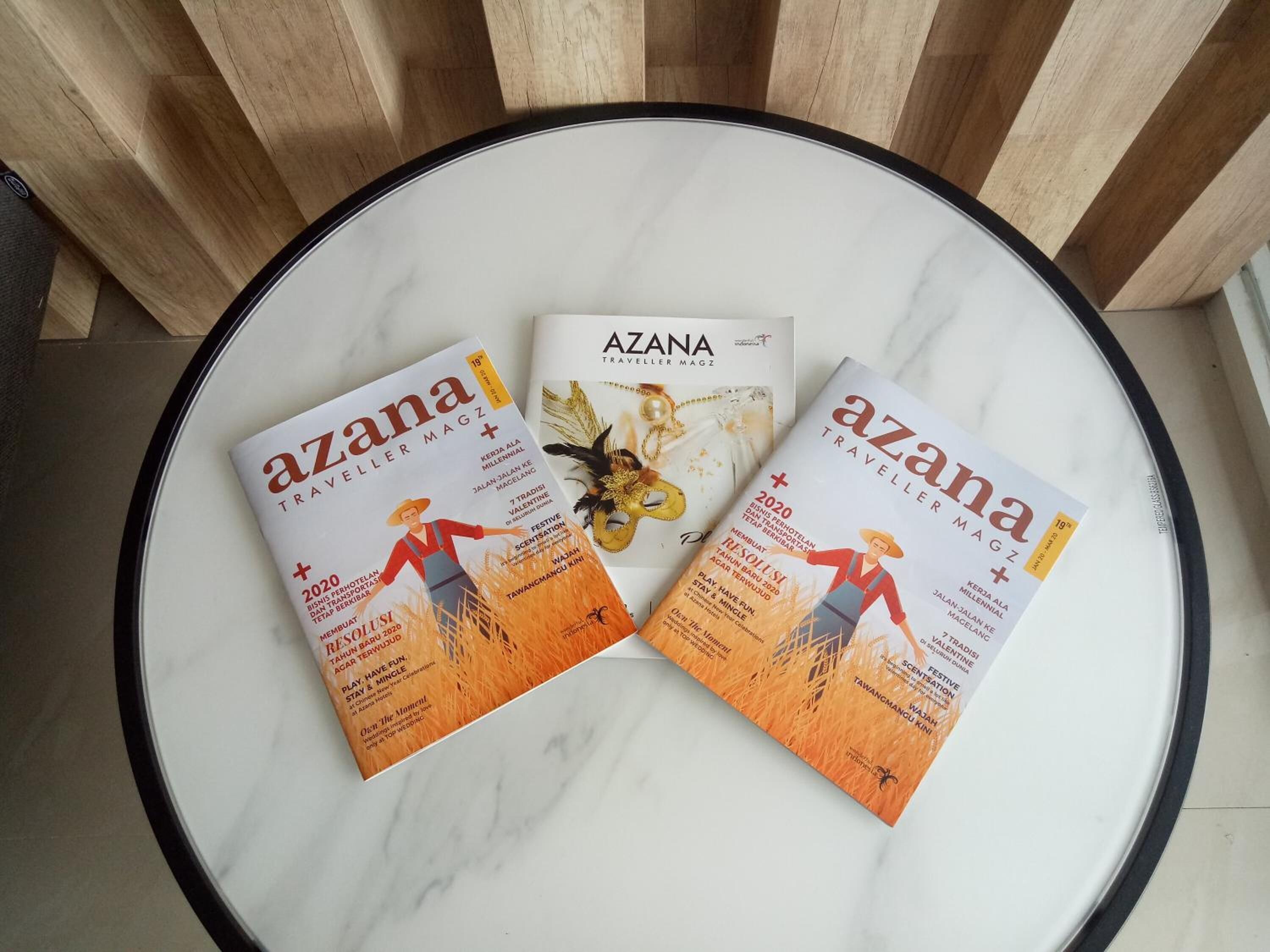 Three 'Azana Traveller Magazine' covers on a round table.