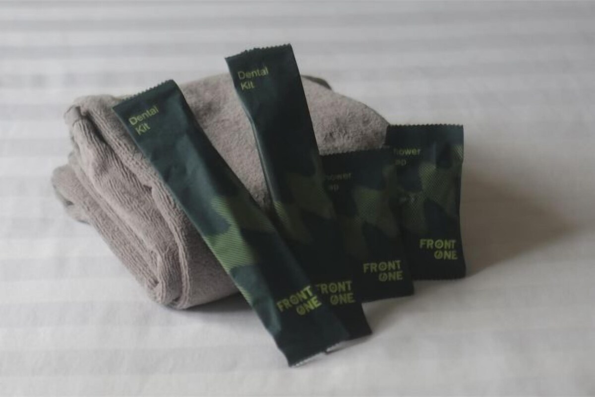 A folded towel and three dental kits labeled "FRONT ONE" on a white surface.