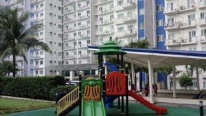 Ein Spielplatz mit Rutschen und Klettergerüsten, umgeben von einem Wohngebäude mit Balkonen.