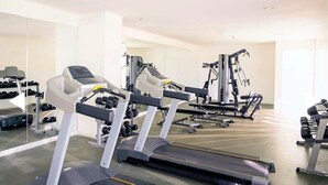 Ein Fitnessstudio mit Laufbändern, Kraftgeräten und Kurzhanteln.