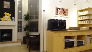 A living room with a fireplace, a coffee station, and a bookshelf.