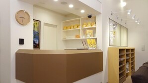 A reception area with a brown counter, a clock, and shelves with yellow items.