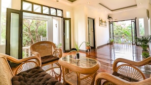 Una habitación amplia con muebles de mimbre, una mesa de vidrio y plantas en macetas.