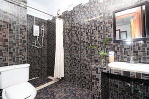 A bathroom with a tiled shower, a toilet, a sink, and a mirror. - Villa Pumpkin (Siem Reap)