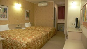 A hotel room with two beds, a desk, a computer, and a refrigerator.