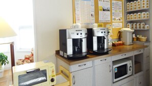 A kitchenette with a microwave, toaster, and two coffee makers on the counter.