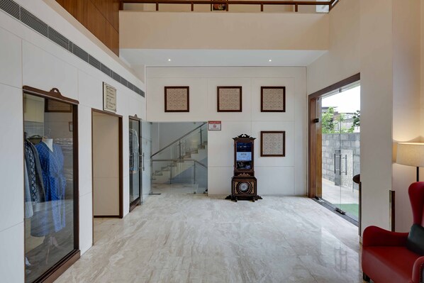 A hotel lobby with a marble floor, a staircase, a clock, and a red chair. - Shahpura Residency (Jaipur)